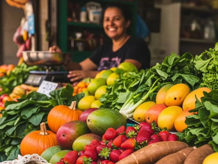Banca de feira livre brasileira com frutas e legumes da estação, sacola reutilizável, luz natural, representando consumo local, sazonal e responsável.