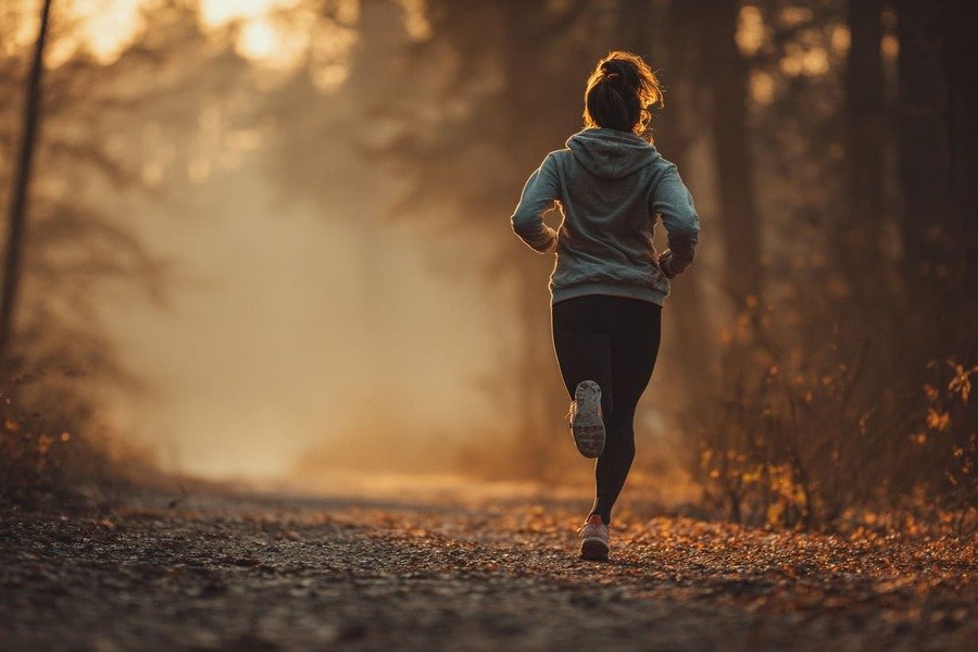 Corredor em movimento leve em trilha ao amanhecer, simbolizando energia e bem-estar.
