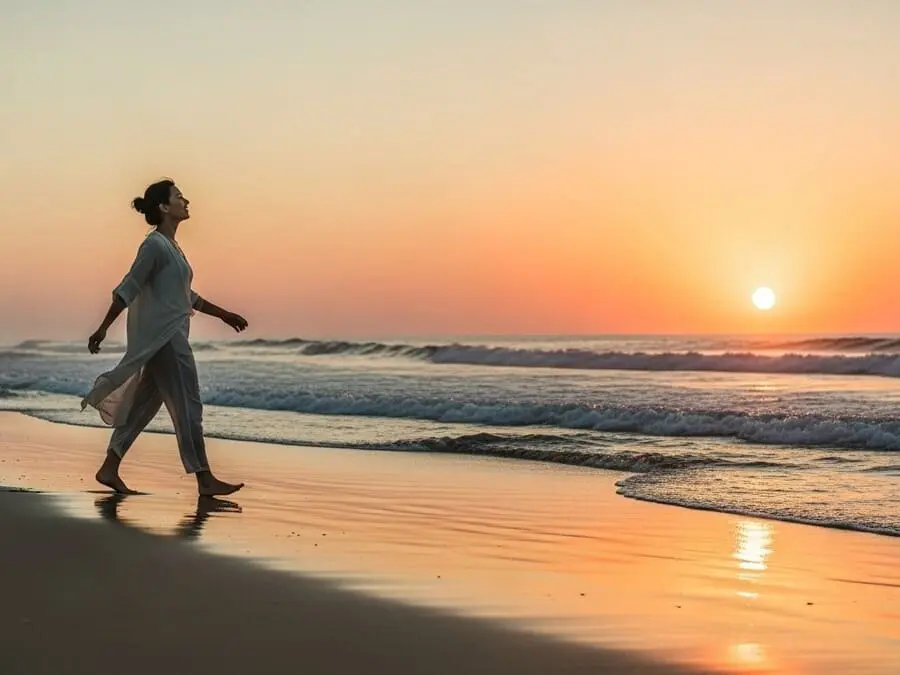 Pessoa caminhando na praia ao pôr do sol, representando equilíbrio e transformação.