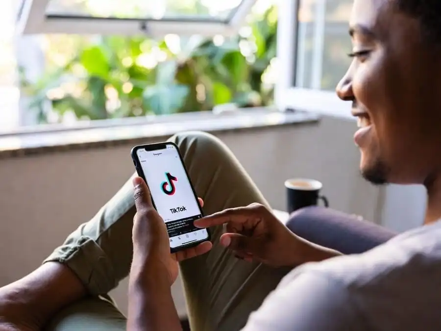 Pessoa relaxada no sofá segurando celular, prestes a fechar o app sem postar, expressão de alívio e autocuidado digital.