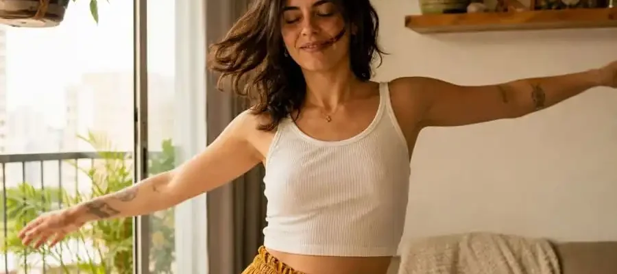 Pessoa em casa começando a dançar com expressão de alívio e leveza, luz natural suave em ambiente brasileiro, simbolizando redução da ansiedade através do movimento corporal.