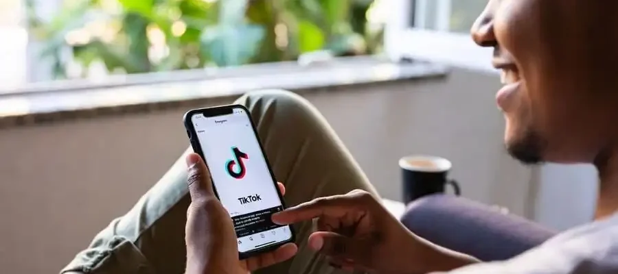 Pessoa relaxada no sofá segurando celular, prestes a fechar o app sem postar, expressão de alívio e autocuidado digital.