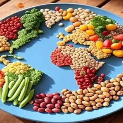 Mapa-múndi artístico formado por alimentos vegetais sobre prato azul: continentes criados com feijão vermelho, feijão carioca, lentilhas, grão-de-bico, ervilhas, brócolis, cenouras baby, vagens, milho e outros grãos e legumes frescos, simbolizando alimentação global e diversidade vegetal.